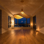 Lustre pendente de bambu Xian aceso em sala de estar ao entardecer